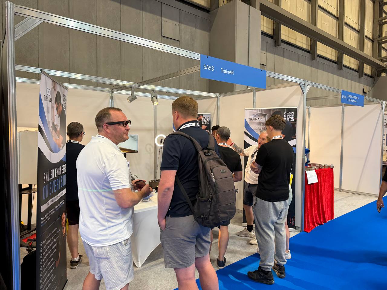 A busy TrainAR stand at InstallerSHOW 2026, NEC Birmingham, with engineers gathered to see the AR training glasses in action